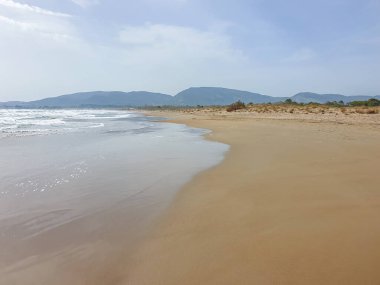 Kumsaldaki bulutlar. Denizi ve kumu seyret. Rüzgâr sörfçüleri suda. Sörfçüler için harika bir hava, Lagana Sahili, İyon Adası Zakynthos, Yunanistan 'da sahile gidenler için kötü hava