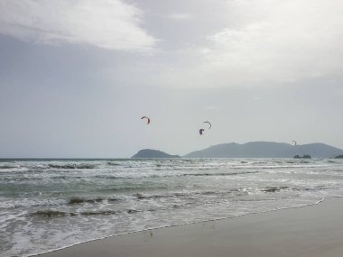 Kumsaldaki bulutlar. Denizi ve kumu seyret. Rüzgâr sörfçüleri suda. Sörfçüler için harika bir hava, Lagana Sahili, İyon Adası Zakynthos, Yunanistan 'da sahile gidenler için kötü hava