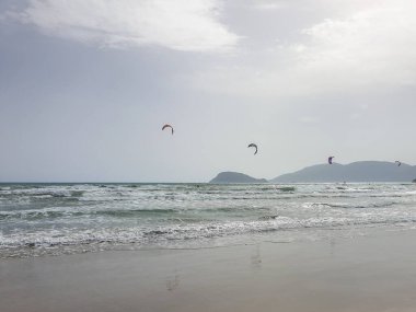 Kumsaldaki bulutlar. Denizi ve kumu seyret. Rüzgâr sörfçüleri suda. Sörfçüler için harika bir hava, Lagana Sahili, İyon Adası Zakynthos, Yunanistan 'da sahile gidenler için kötü hava