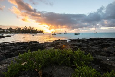 Balıkçı tekneleri olan küçük bir liman manzaralı bir manzara. Mauritius, Malheureux Burnu 'nda günbatımı manzaralı tropikal bir manzara.