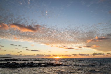 Işık dalgalarıyla denizin üzerinde gün doğumu. Lav taşlı kum kumsalı ve mavi suyla alternatif mavi su. Hint Okyanusu 'nda bir ada, beklenmedik bir plaj, Trou dEau Douce, Mauritius, Afrika