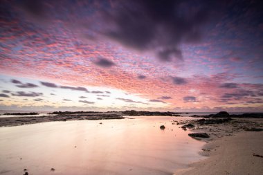Işık dalgalarıyla denizin üzerinde gün doğumu. Lav taşlı kum kumsalı ve mavi suyla alternatif mavi su. Hint Okyanusu 'nda bir ada, beklenmedik bir plaj, Trou dEau Douce, Mauritius, Afrika