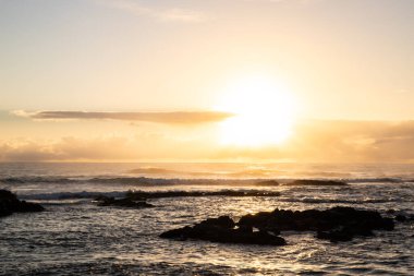 Işık dalgalarıyla denizin üzerinde gün doğumu. Lav taşlı kum kumsalı ve mavi suyla alternatif mavi su. Hint Okyanusu 'nda bir ada, beklenmedik bir plaj, Trou dEau Douce, Mauritius, Afrika