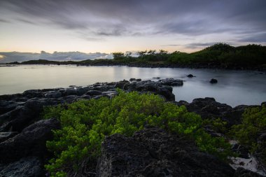 Denizin üzerinde uzun süre güneş doğuyor. Lav taşlı kum kumsalı ve mavi suyla alternatif mavi su. Hint Okyanusu 'nda bir ada, beklenmedik bir plaj, Trou dEau Douce, Mauritius, Afrika