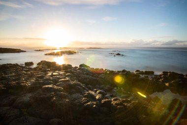Küçük dalgalar lav kayalarını denizle çevreler. Hint Okyanusu 'ndaki bir adanın kıyı şeridi. Sabah gün doğumu, sahilde güzel sıcak bir ışık... Trou d 'Eau Douce, Mauritius
