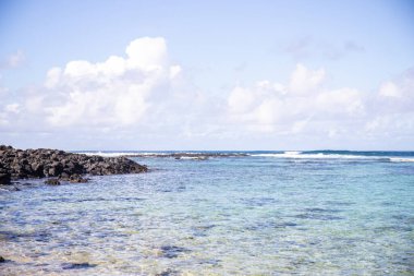 Küçük dalgalar lav kayalarını denizle çevreler. Hint Okyanusu 'ndaki bir adanın kıyı şeridi. Sabah gün doğumu, sahilde güzel sıcak bir ışık... Trou d 'Eau Douce, Mauritius