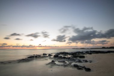 Küçük dalgalar lav kayalarını denizle çevreler. Hint Okyanusu 'ndaki bir adanın kıyı şeridi. Sabah gün doğumu, sahilde güzel sıcak bir ışık... Trou d 'Eau Douce, Mauritius