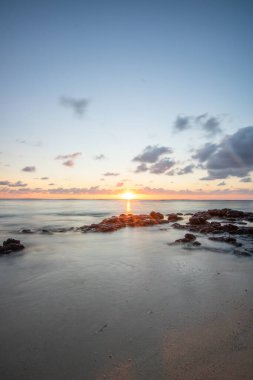 Küçük dalgalar lav kayalarını denizle çevreler. Hint Okyanusu 'ndaki bir adanın kıyı şeridi. Sabah gün doğumu, sahilde güzel sıcak bir ışık... Trou d 'Eau Douce, Mauritius