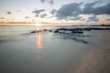 Küçük dalgalar lav kayalarını denizle çevreler. Hint Okyanusu 'ndaki bir adanın kıyı şeridi. Sabah gün doğumu, sahilde güzel sıcak bir ışık... Trou d 'Eau Douce, Mauritius