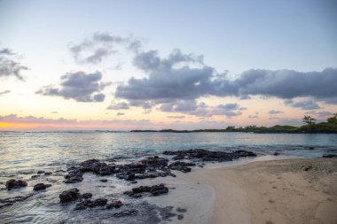 Küçük dalgalar lav kayalarını denizle çevreler. Hint Okyanusu 'ndaki bir adanın kıyı şeridi. Sabah gün doğumu, sahilde güzel sıcak bir ışık... Trou d 'Eau Douce, Mauritius