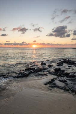 Küçük dalgalar lav kayalarını denizle çevreler. Hint Okyanusu 'ndaki bir adanın kıyı şeridi. Sabah gün doğumu, sahilde güzel sıcak bir ışık... Trou d 'Eau Douce, Mauritius
