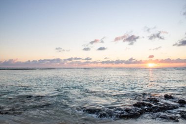 Küçük dalgalar lav kayalarını denizle çevreler. Hint Okyanusu 'ndaki bir adanın kıyı şeridi. Sabah gün doğumu, sahilde güzel sıcak bir ışık... Trou d 'Eau Douce, Mauritius