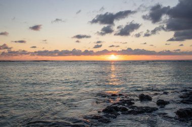 Küçük dalgalar lav kayalarını denizle çevreler. Hint Okyanusu 'ndaki bir adanın kıyı şeridi. Sabah gün doğumu, sahilde güzel sıcak bir ışık... Trou d 'Eau Douce, Mauritius