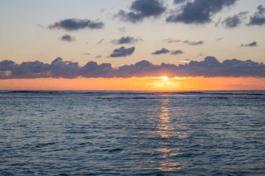 Küçük dalgalar lav kayalarını denizle çevreler. Hint Okyanusu 'ndaki bir adanın kıyı şeridi. Sabah gün doğumu, sahilde güzel sıcak bir ışık... Trou d 'Eau Douce, Mauritius