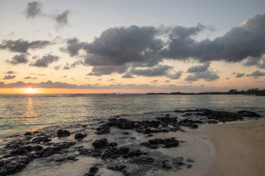 Küçük dalgalar lav kayalarını denizle çevreler. Hint Okyanusu 'ndaki bir adanın kıyı şeridi. Sabah gün doğumu, sahilde güzel sıcak bir ışık... Trou d 'Eau Douce, Mauritius