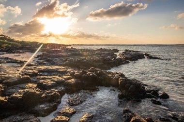 Hint Okyanusu 'ndaki bir adada çekilen manzara. Sahildeki bu yeşil çayır, ufukta gün doğumuyla Mauritius, Trou d 'Eau Douce' deki lav kayaları arasında uzanır.