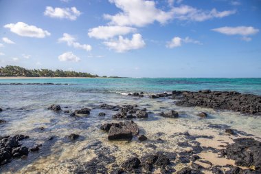Küçük dalgalar lav kayalarını denizle çevreler. Hint Okyanusu 'ndaki bir adanın kıyı şeridi. Sabah gün doğumu, sahilde güzel sıcak bir ışık... Trou d 'Eau Douce, Mauritius