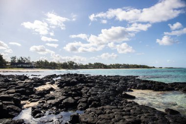 Küçük dalgalar lav kayalarını denizle çevreler. Hint Okyanusu 'ndaki bir adanın kıyı şeridi. Sabah gün doğumu, sahilde güzel sıcak bir ışık... Trou d 'Eau Douce, Mauritius