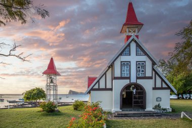 Landscape with a view of a small church with a red roof. Bay and small harbor with fishing boats. Tropical landscape with sunset view, Notre-Dame Auxiliatrice de Cap Malheureux, Mauritius clipart