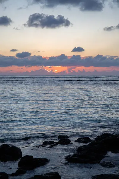 Küçük dalgalar lav kayalarını denizle çevreler. Hint Okyanusu 'ndaki bir adanın kıyı şeridi. Sabah gün doğumu, sahilde güzel sıcak bir ışık... Trou d 'Eau Douce, Mauritius