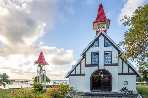 stock image Landscape with a view of a small church with a red roof. Bay and small harbor with fishing boats. Tropical landscape with sunset view, Notre-Dame Auxiliatrice de Cap Malheureux, Mauritius