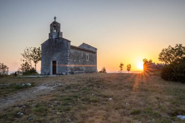 Önünde bir patika olan küçük tarihi bir kilise. Kilise, gündoğumunda ve Akdeniz manzarasında bir uçurumun üzerinde duruyor. Hırvatistan 'ın Istria kentinin tarihi Bresc köyü