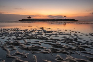 Sahilde küçük tapınaklarla muhteşem bir gün doğumu. Ufukta deniz manzarası var. Sanur, Bali, Endonezya