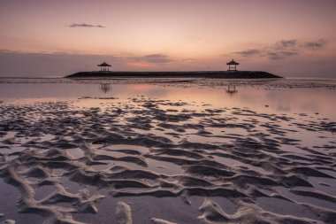 Sahilde küçük tapınaklarla muhteşem bir gün doğumu. Ufukta deniz manzarası var. Sanur, Bali, Endonezya