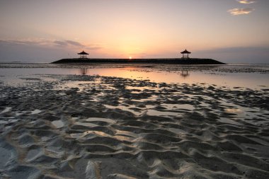 Sahilde küçük tapınaklarla muhteşem bir gün doğumu. Ufukta deniz manzarası var. Sanur, Bali, Endonezya