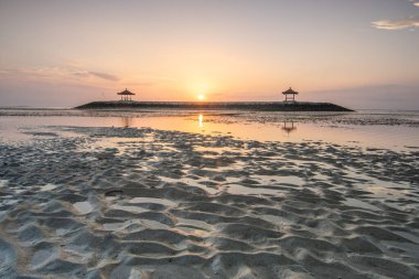 Sahilde küçük tapınaklarla muhteşem bir gün doğumu. Ufukta deniz manzarası var. Sanur, Bali, Endonezya