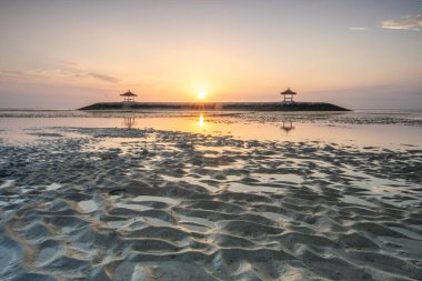 Sahilde küçük tapınaklarla muhteşem bir gün doğumu. Ufukta deniz manzarası var. Sanur, Bali, Endonezya
