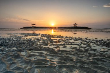 Sahilde küçük tapınaklarla muhteşem bir gün doğumu. Ufukta deniz manzarası var. Sanur, Bali, Endonezya