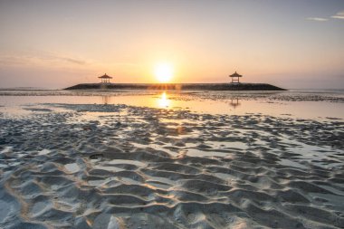 Sahilde küçük tapınaklarla muhteşem bir gün doğumu. Ufukta deniz manzarası var. Sanur, Bali, Endonezya