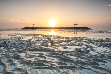 Sahilde küçük tapınaklarla muhteşem bir gün doğumu. Ufukta deniz manzarası var. Sanur, Bali, Endonezya