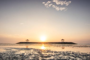 Sahilde küçük tapınaklarla muhteşem bir gün doğumu. Ufukta deniz manzarası var. Sanur, Bali, Endonezya