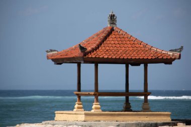 Sahilde muhteşem bir gün doğumu. Küçük tapınakları var. Dalgakıran olarak inşa edilmiş. Ufukta deniz manzarası var. Sanur, Bali, Endonezya