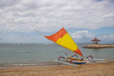 Sahilde küçük tapınaklar ve geleneksel balıkçı teknesi Jukung 'la muhteşem bir gün doğumu. Ufukta deniz manzarası var. Sanur, Bali, Endonezya