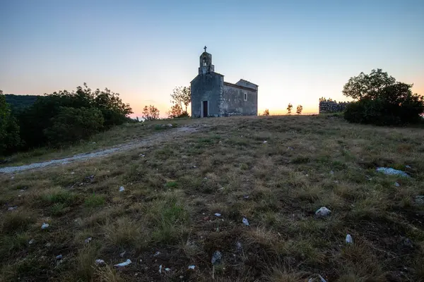 Önünde bir patika olan küçük tarihi bir kilise. Kilise, gündoğumunda ve Akdeniz manzarasında bir uçurumun üzerinde duruyor. Hırvatistan 'ın Istria kentinin tarihi Bresc köyü