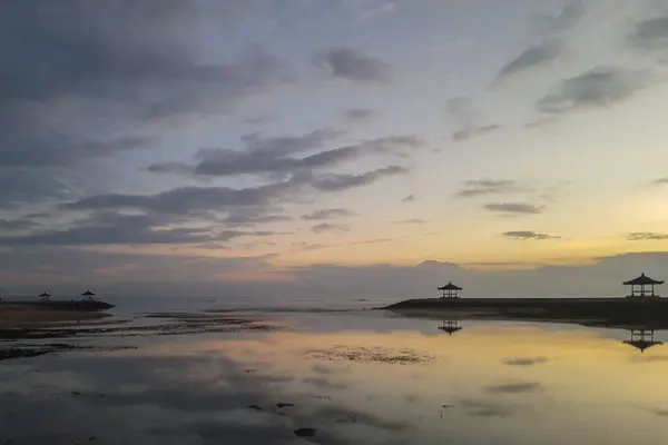 stock image Fantastic sunrise on the beach with small temples. View of the sea to the horizon. Sanur, Bali, Indonesia