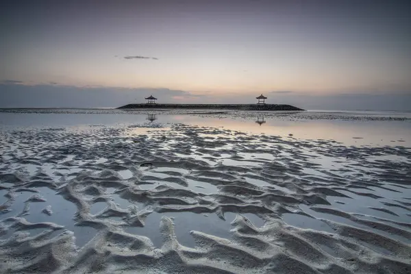 stock image Fantastic sunrise on the beach with small temples. View of the sea to the horizon. Sanur, Bali, Indonesia