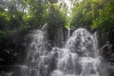 Güzel gizli şelale bir çok kattan aşağı düşüyor. Siyah lav taşlarıyla çevrili Kanto Lampo, Bali, Endonezya