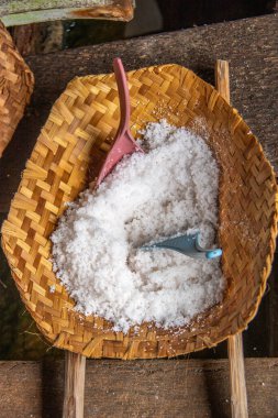  Geleneksel deniz tuzu üretimi siyah lav plajında bir tuz çiftçisi tarafından yapılıyor. Bali, Endonezya