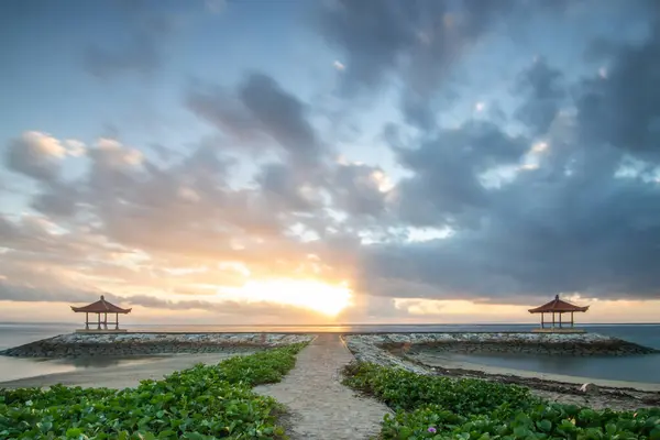 stock image Fantastic sunrise on the beach with small temples and built as a breakwater. View of the sea to the horizon. Sanur, Bali, Indonesia