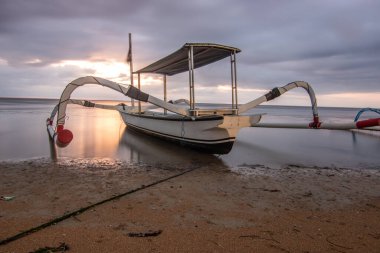 Denizde jukung, tipik bir plaj manzarası. Gün doğumunda balıkçı teknesi. Sanur, Bali, Endonezya manzarası