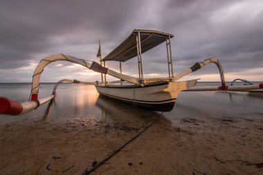 Denizde jukung, tipik bir plaj manzarası. Gün doğumunda balıkçı teknesi. Sanur, Bali, Endonezya manzarası