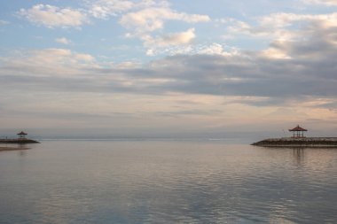 Sabahları deniz manzarası çok güzeldir. Dalgakıran ve sakin sularda gökyüzünün yansıması olan tropik kumlu bir sahil. Sanur, Bali, Endonezya