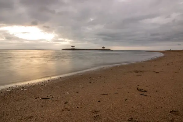 Sabahları deniz manzarası çok güzeldir. Dalgakıran ve sakin sularda gökyüzünün yansıması olan tropik kumlu bir sahil. Sanur, Bali, Endonezya