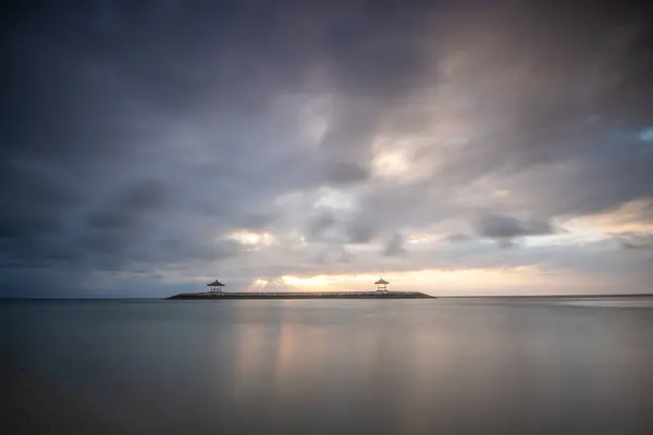 Sabahları deniz manzarası çok güzeldir. Dalgakıran ve sakin sularda gökyüzünün yansıması olan tropik kumlu bir sahil. Sanur, Bali, Endonezya