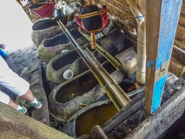 Geleneksel deniz tuzu üretimi siyah lav plajında bir tuz çiftçisi tarafından yapılıyor. Bali, Endonezya