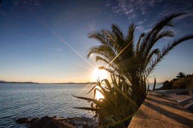 Kumlu bir sahildeki kayaların arasından gün batımına bak. Manzara, Ouranoupoli, Selanik, Orta Makedonya ve Yunanistan kıyılarındaki engin deniz manzarası ile çekildi